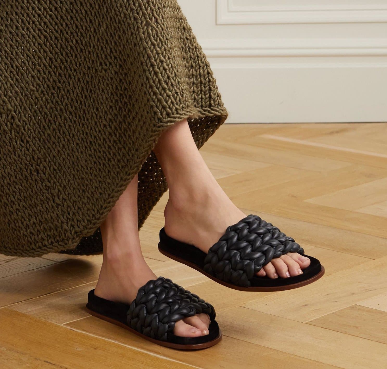 The Chloé Kacey slide sandals feature a braided woven leather strap set on a cushioned footbed, balancing artisanal texture with everyday comfort