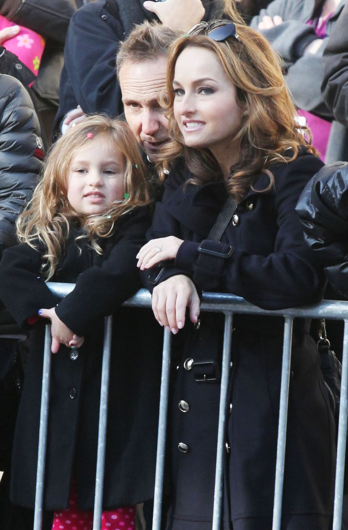 Giada De Laurentiis, bundled up in a chic belted black coat, watches the festivities alongside daughter Jade and then-husband Todd Thompson at the Macy’s Thanksgiving Day Parade, all three matching in cozy, cold-weather style