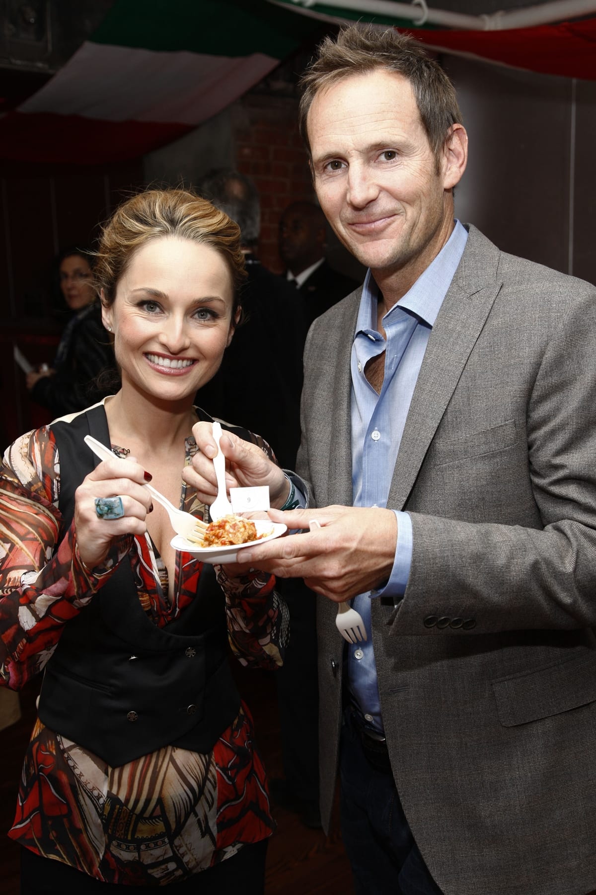 Giada De Laurentiis shares a playful moment over pasta with then-husband Todd Thompson, wearing a bold, printed blouse layered under a black tailored vest and accessorized with a statement turquoise ring