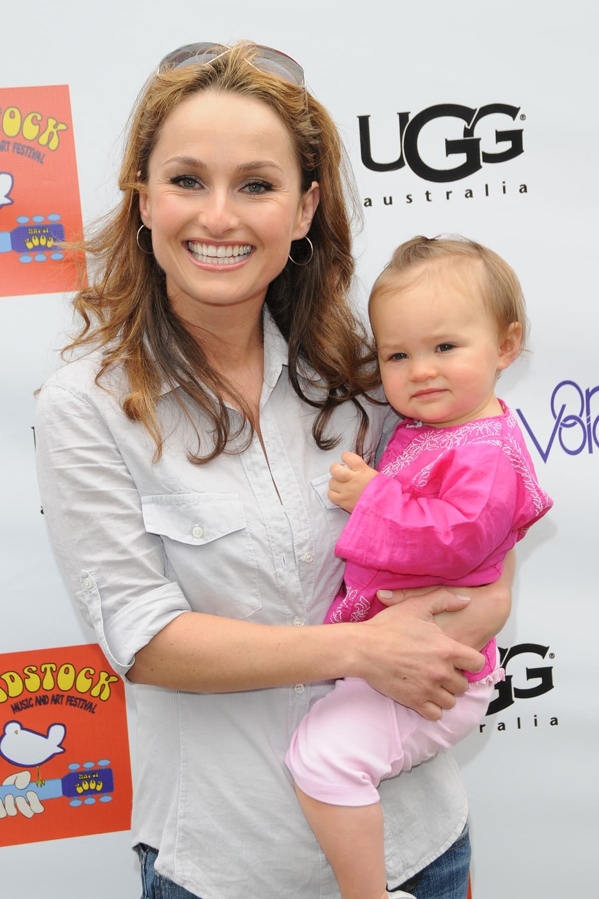 Giada De Laurentiis beams with pride as she holds baby Jade, dressed casually in a light button-down shirt and jeans while attending a family-friendly event shortly after becoming a mom at 37