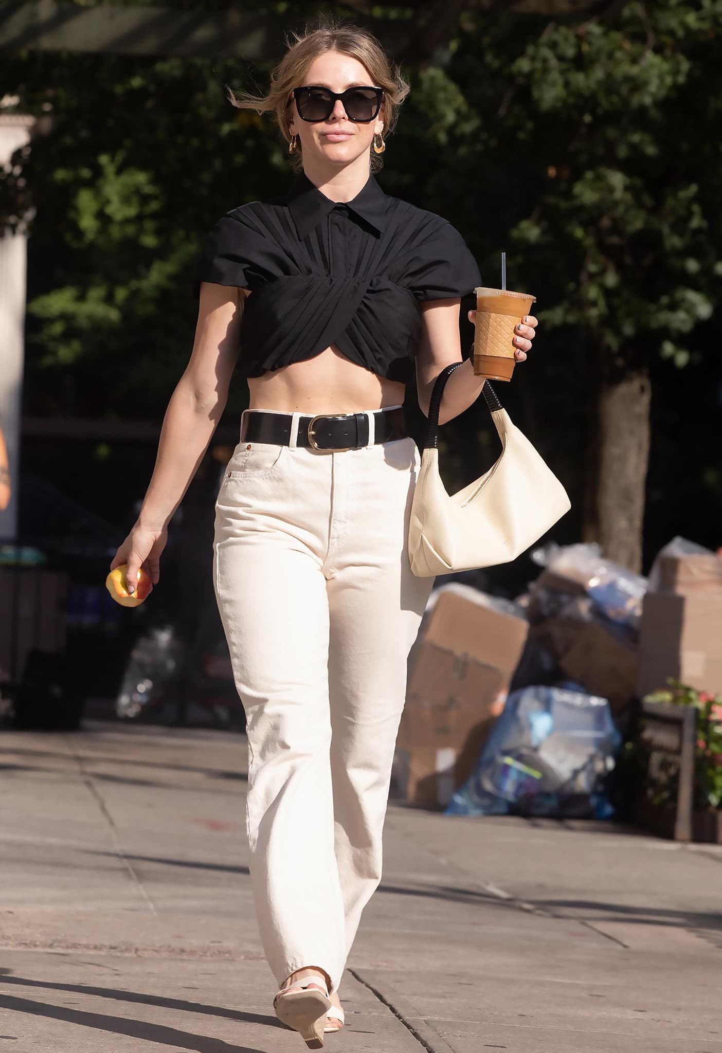 Julianne Hough heads to her Broadway rehearsal on August 2, 2022 in a black cropped Brandon Maxwell top, creamy high-waisted jeans, a bold leather belt, white open-toe sandals, and oversized shades—nailing contrast and casual chic