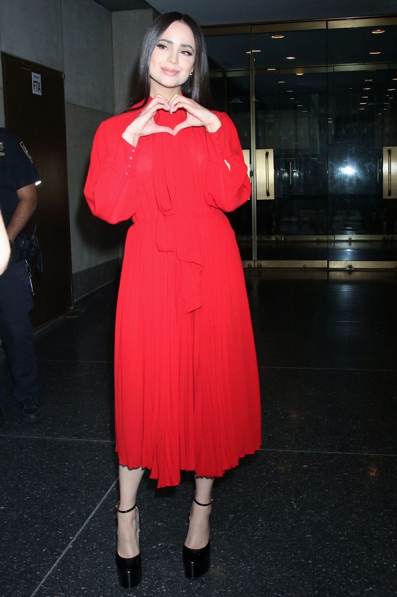 Sofia Carson lights up the Today Show in a bold red Valentino dress, grounded by towering black platform pumps with thin ankle straps