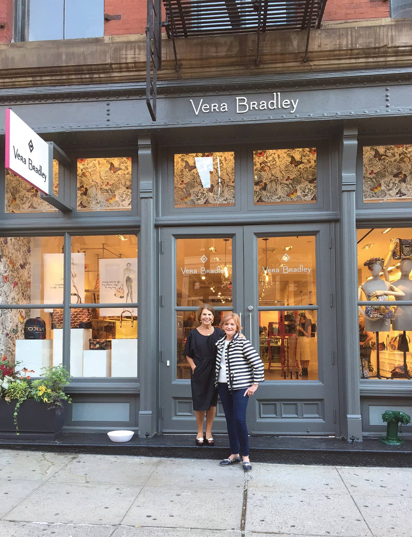 Vera Bradley co-founders Barbara Bradley Baekgaard and Patricia Miller pose outside a stylish Vera Bradley storefront