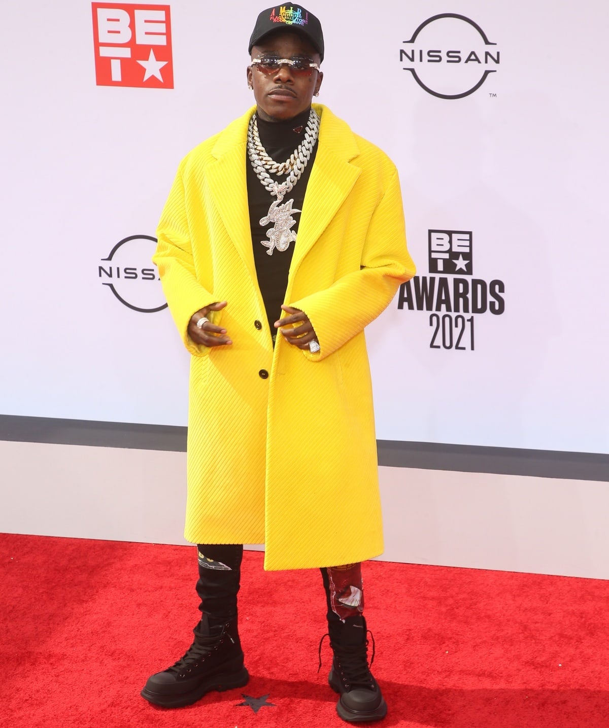 DaBaby turns heads at the 2021 BET Awards on June 27, 2021, in a vibrant yellow overcoat, stacked chains, graphic pants, and rugged black combat boots that added an edge to his bold red carpet look