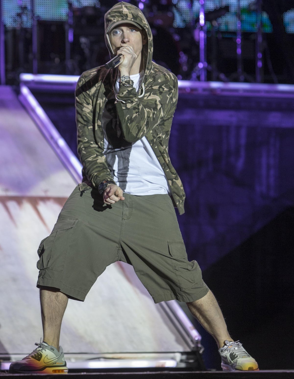 Performing at the 2013 Reading and Leeds Festival, Eminem commands the stage in a camo hoodie, cargo shorts, and a bold pair of Nike Air Max sneakers that pop under the spotlight