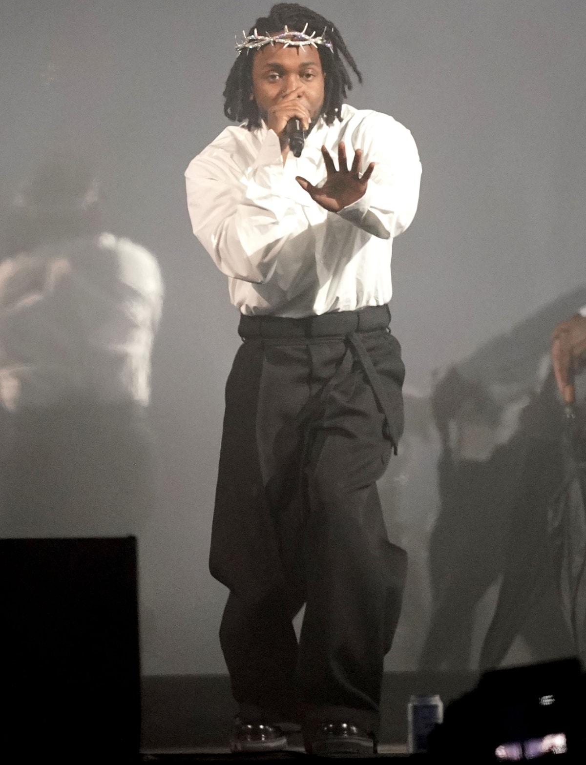 Kendrick Lamar commands the stage at the Glastonbury Festival on June 26, 2022, wearing oversized black trousers, a crisp white shirt, and a symbolic diamond-studded crown of thorns