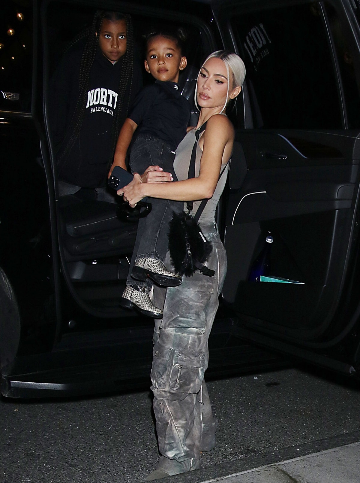 Kim Kardashian steps out in New York City with North and Chicago, pairing her asymmetrical top and distressed cargo pants with sleek gray Balenciaga knife boots for a coordinated family Balenciaga moment