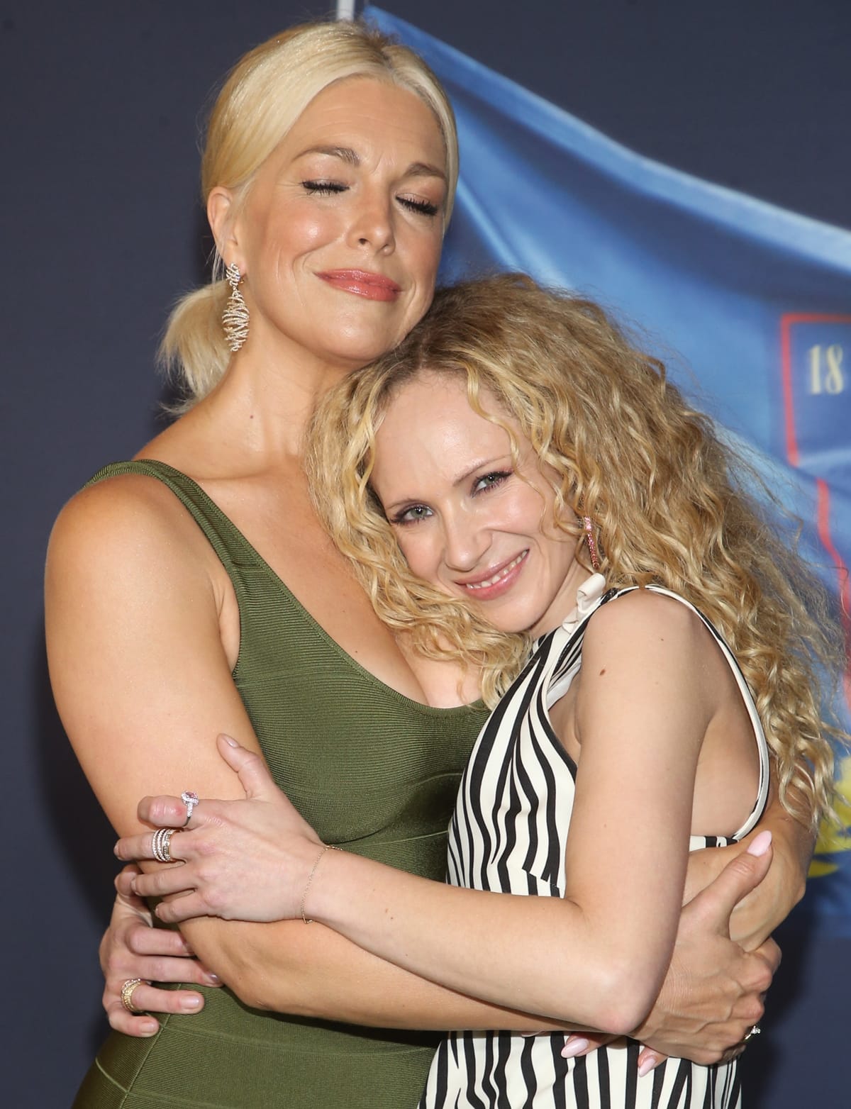 Radiating real-life warmth, Hannah Waddingham and Juno Temple share a heartfelt hug on the red carpet — the towering Ted Lasso star stuns in an olive green dress, while her petite bestie keeps it playful in a black-and-white striped mini