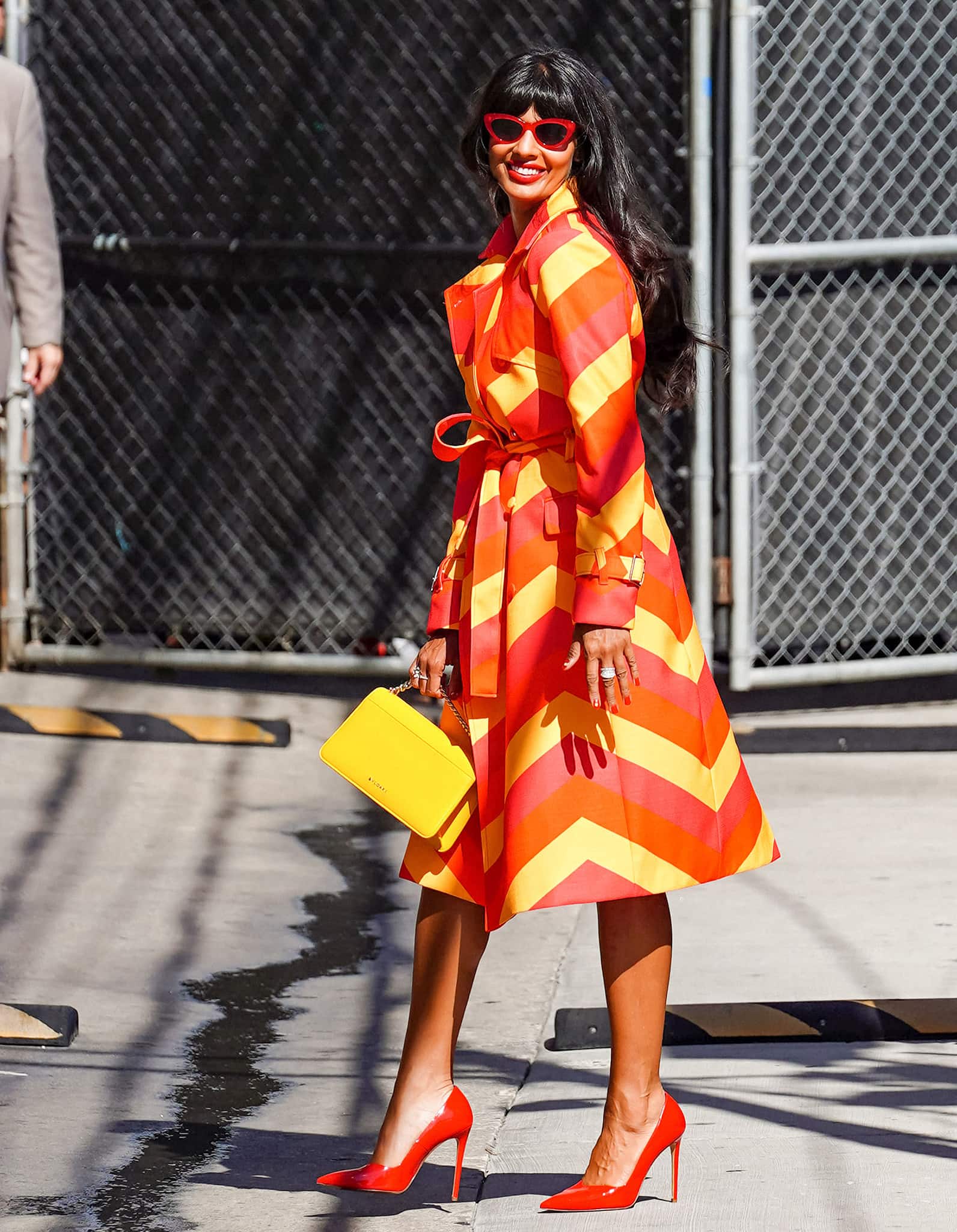 Jameela Jamil pairs her vibrant trench coat with Stuart Weitzman red pumps and yellow Bulgari bag