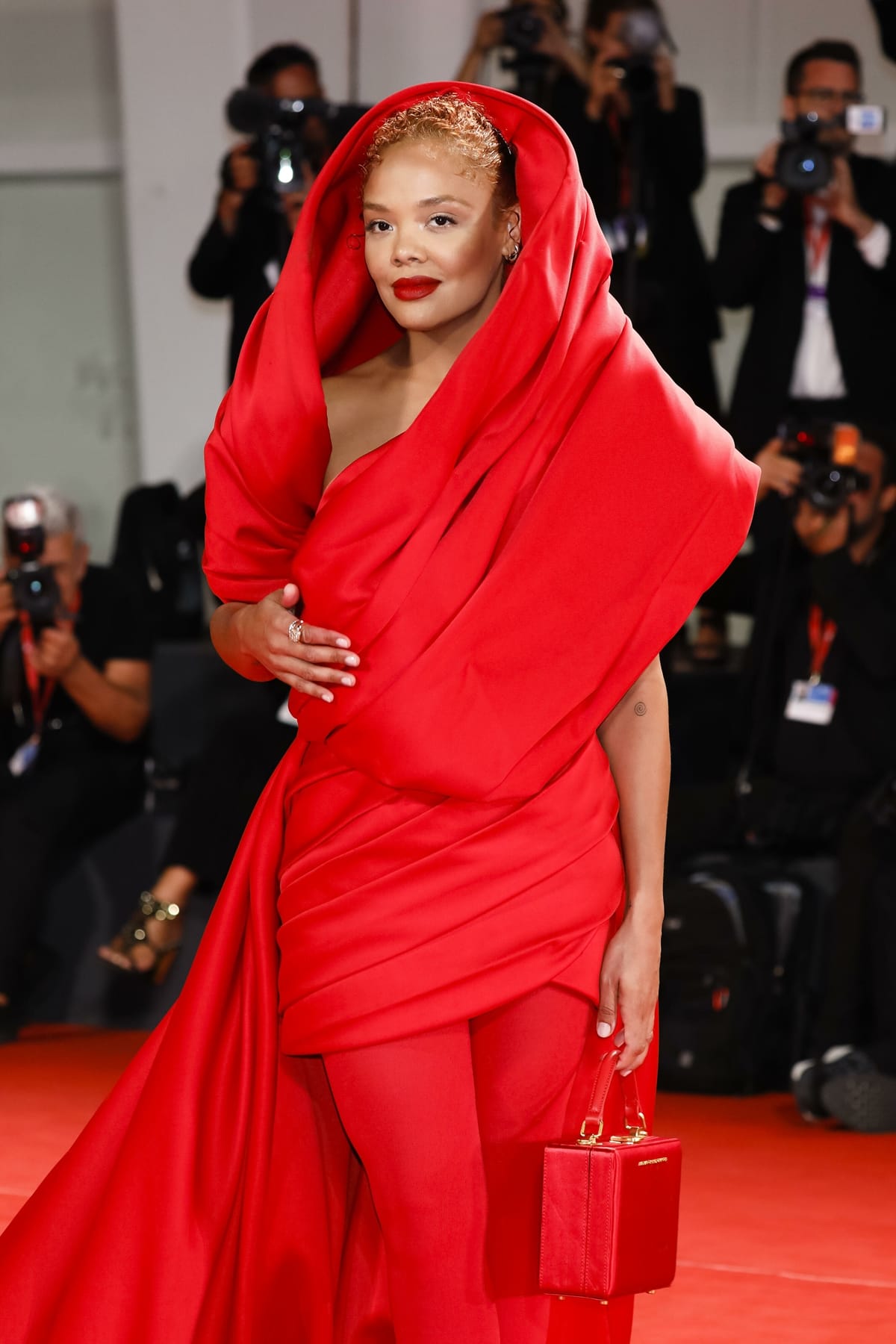 Tessa Thompson totes a red Brandon Blackwood Kendrick trunk bag at the "Bardo" red carpet at the 79th Venice International Film Festival