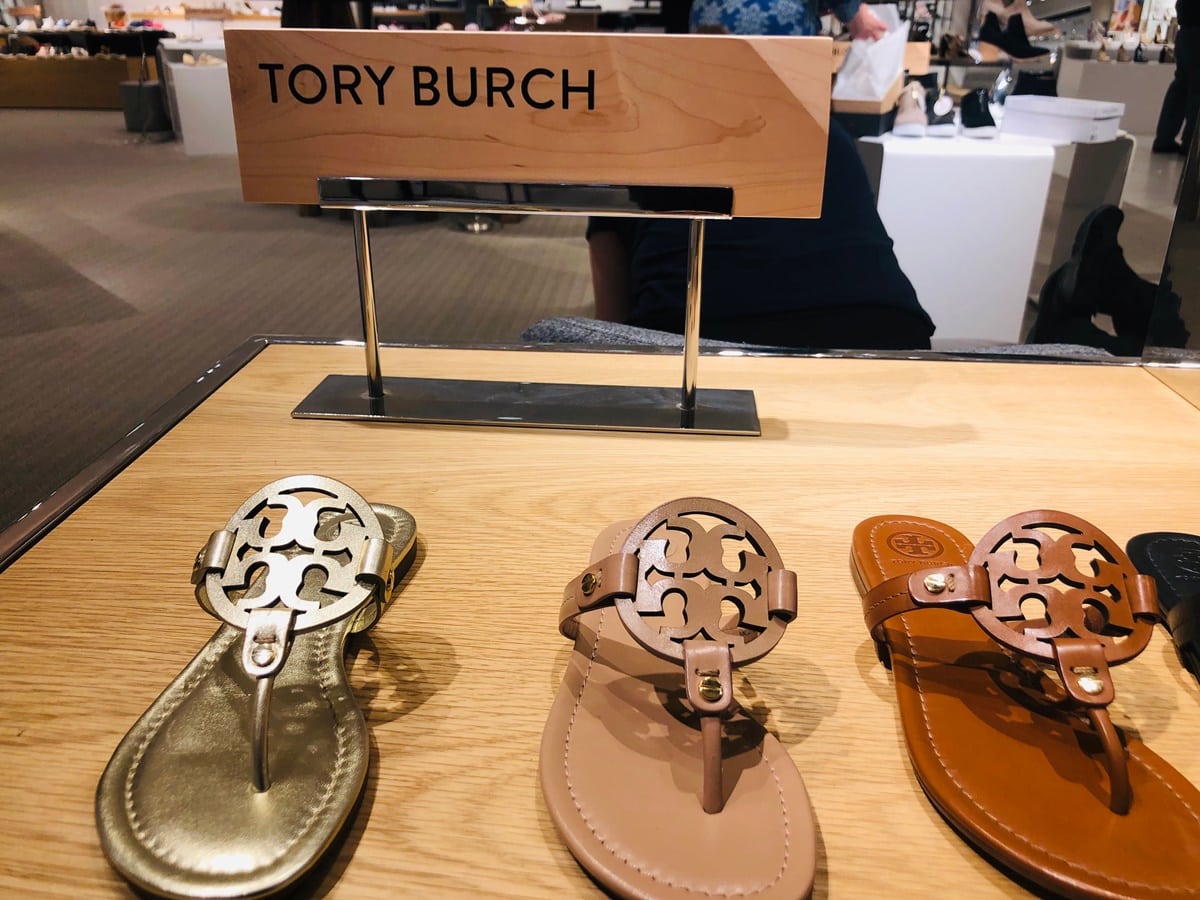 Tory Burch’s iconic Miller sandals—lightweight, comfortable, and instantly recognizable with their laser-cut double-T medallion—on display at a department store