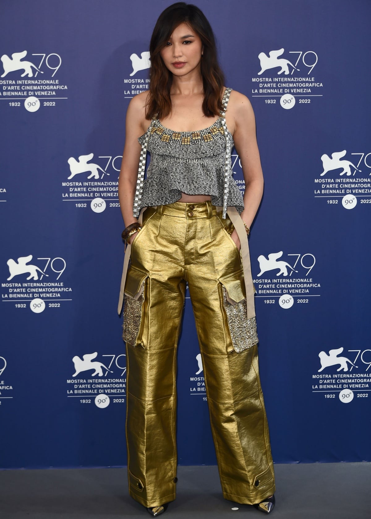 Gemma Chan struck a balance between glamour and grit in a tough-chic Louis Vuitton look, pairing a metallic ruffled crop top with gold cargo trousers and pointed-toe heels that grounded the ensemble with effortless cool