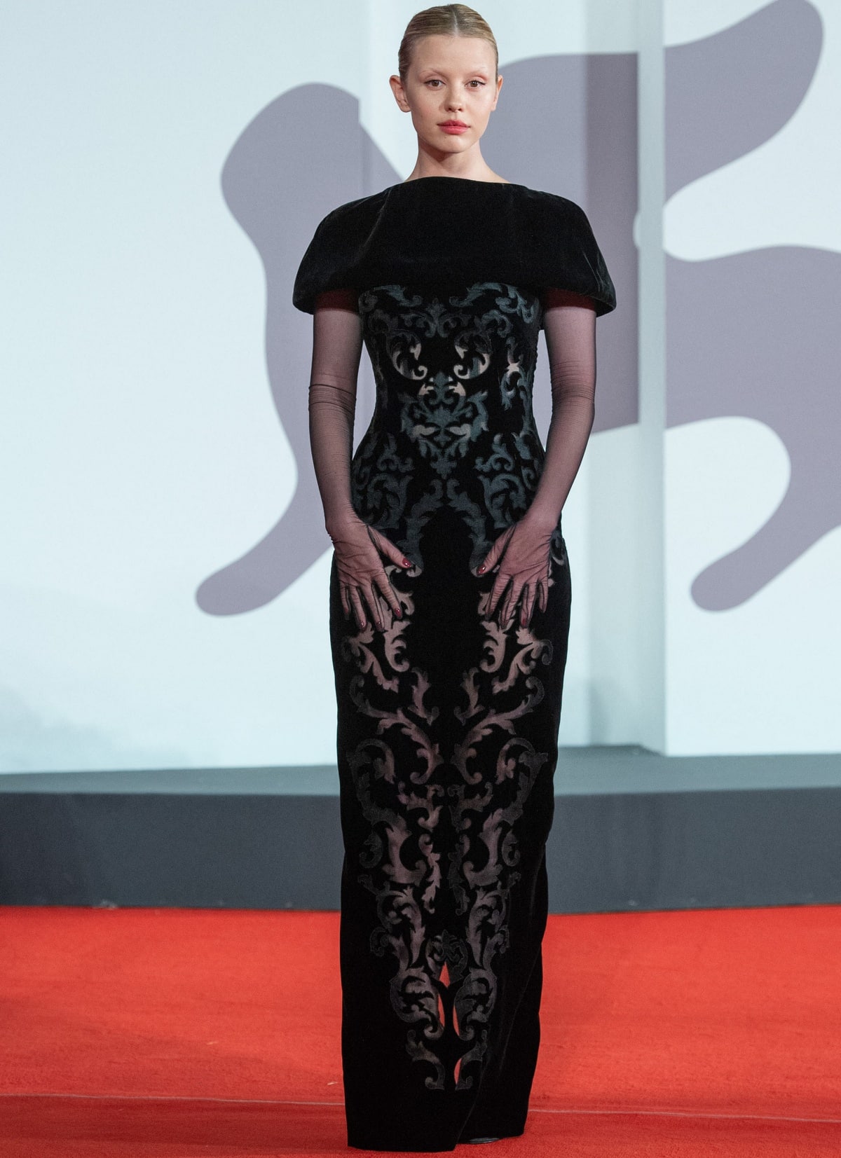 Mia Goth wears a sculptural black velvet Dolce Gabbana Alta Moda gown with sheer opera gloves at the Pearl red-carpet premiere during the 79th Venice International Film Festival on September 3, 2022