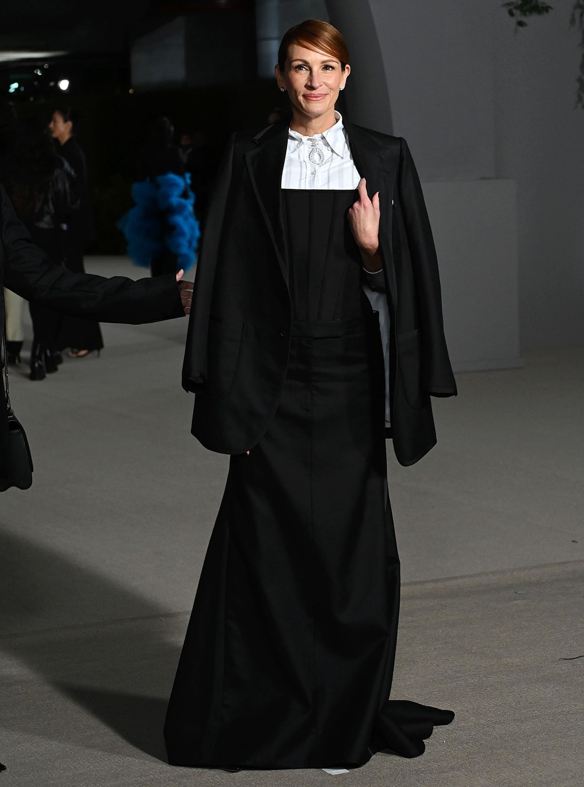 Julia Roberts exudes sophisticated elegance in a tailored black Thom Browne ensemble, featuring a structured corset and floor-length skirt, topped with a draped blazer for a modern twist on formal wear