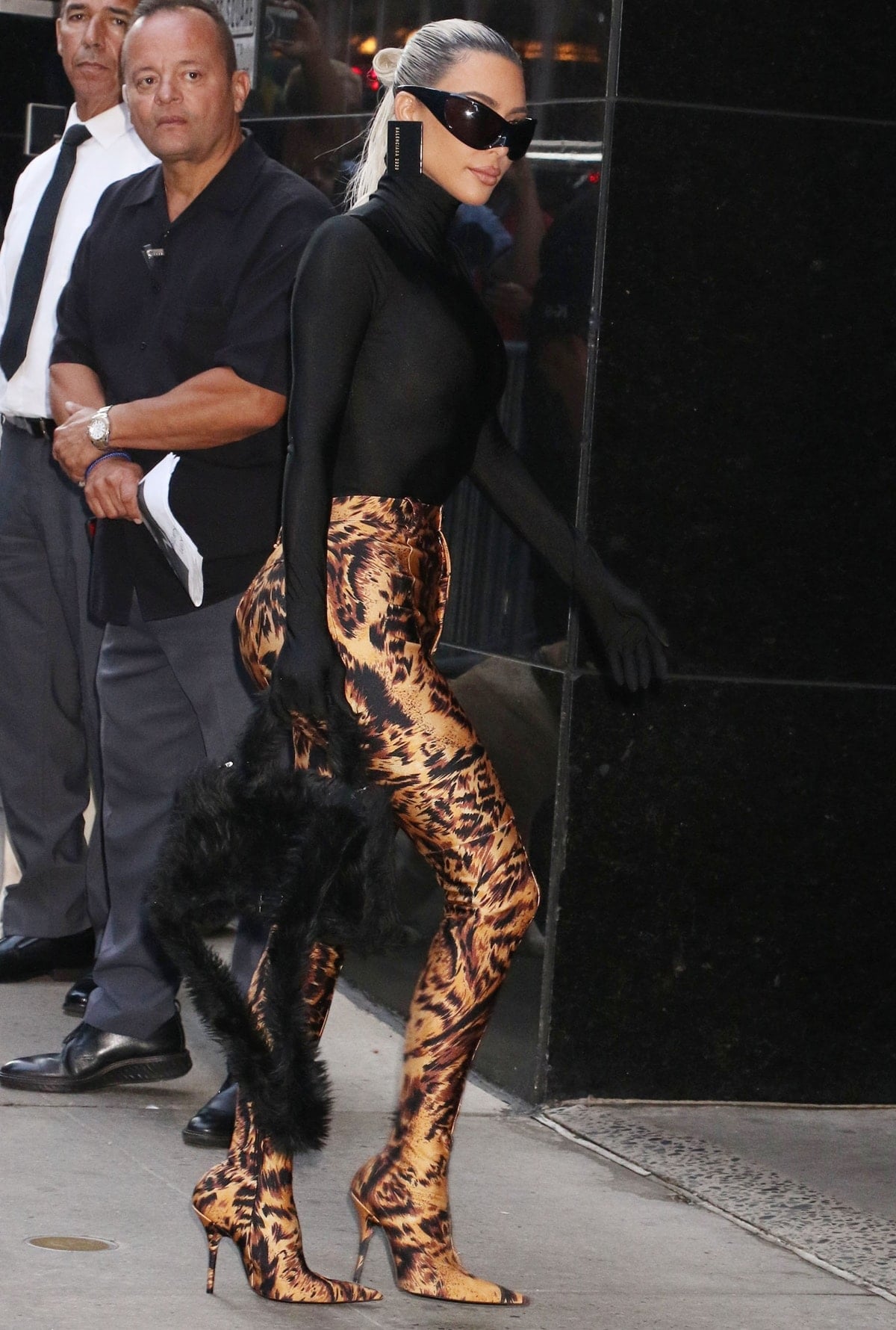 Kim Kardashian completes her bold Balenciaga look with a black mini Hourglass bag crafted from fluffy faux shearling, pairing it with skin-tight leopard Pantaleggings and sleek stiletto heels