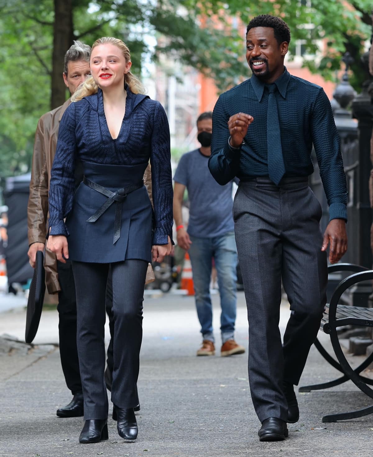 Chloë Grace Moretz and Gary Carr were spotted in coordinated utilitarian looks while filming The Peripheral in New York City on July 18, 2022—Moretz in sleek black boots and tailored layers, Carr in polished dress shoes and a textured shirt, both exuding understated futuristic style