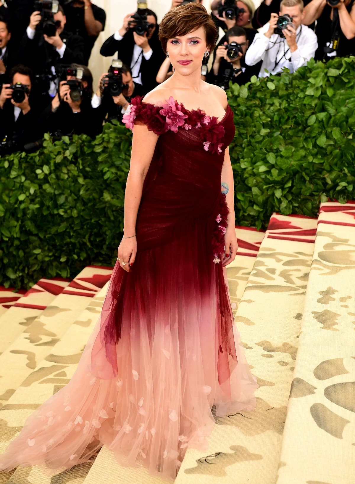 Scarlett Johansson turned heads in a romantic off-the-shoulder burgundy-to-blush ombré Marchesa gown adorned with floral appliqués at the 2018 Met Gala on May 7