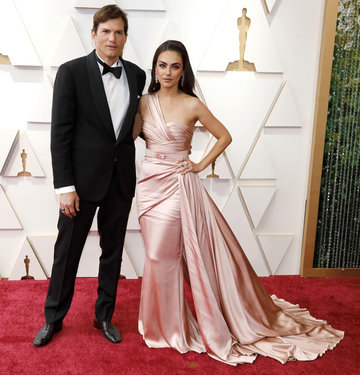 Ashton Kutcher towers over his 5ft 4in wife, Mila Kunis, as the couple stuns at the 94th Annual Academy Awards with Kunis in a flowing pink satin gown that highlights their 10.5-inch height difference