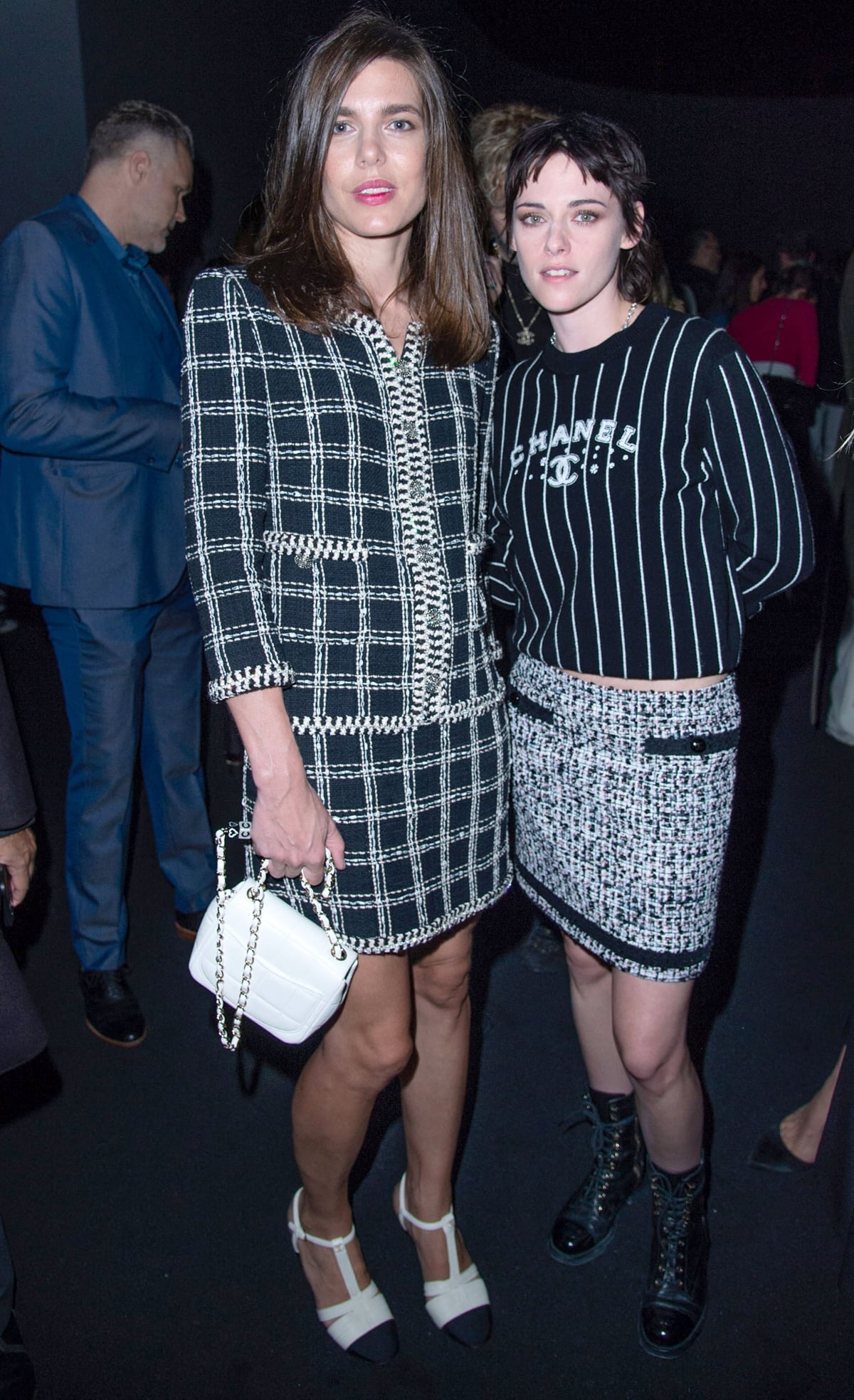 At the Chanel Spring/Summer 2023 show, Charlotte Casiraghi elegantly sports a black-and-white plaid Chanel jacket and matching mini skirt, while Kristen Stewart rocks a cropped striped Chanel top, tweed mini skirt, and combat boots