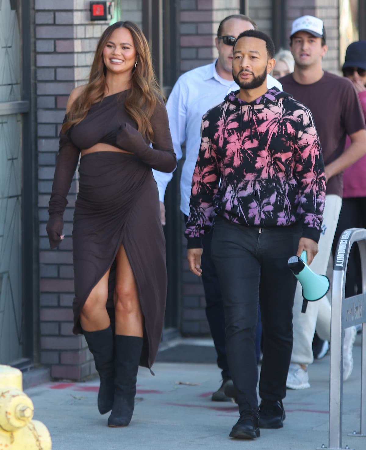 Chrissy Teigen's sophisticated Rick Owens maternity wear and John Legend's vibrant, casual hoodie create a perfectly balanced and stylish dynamic as they stroll together