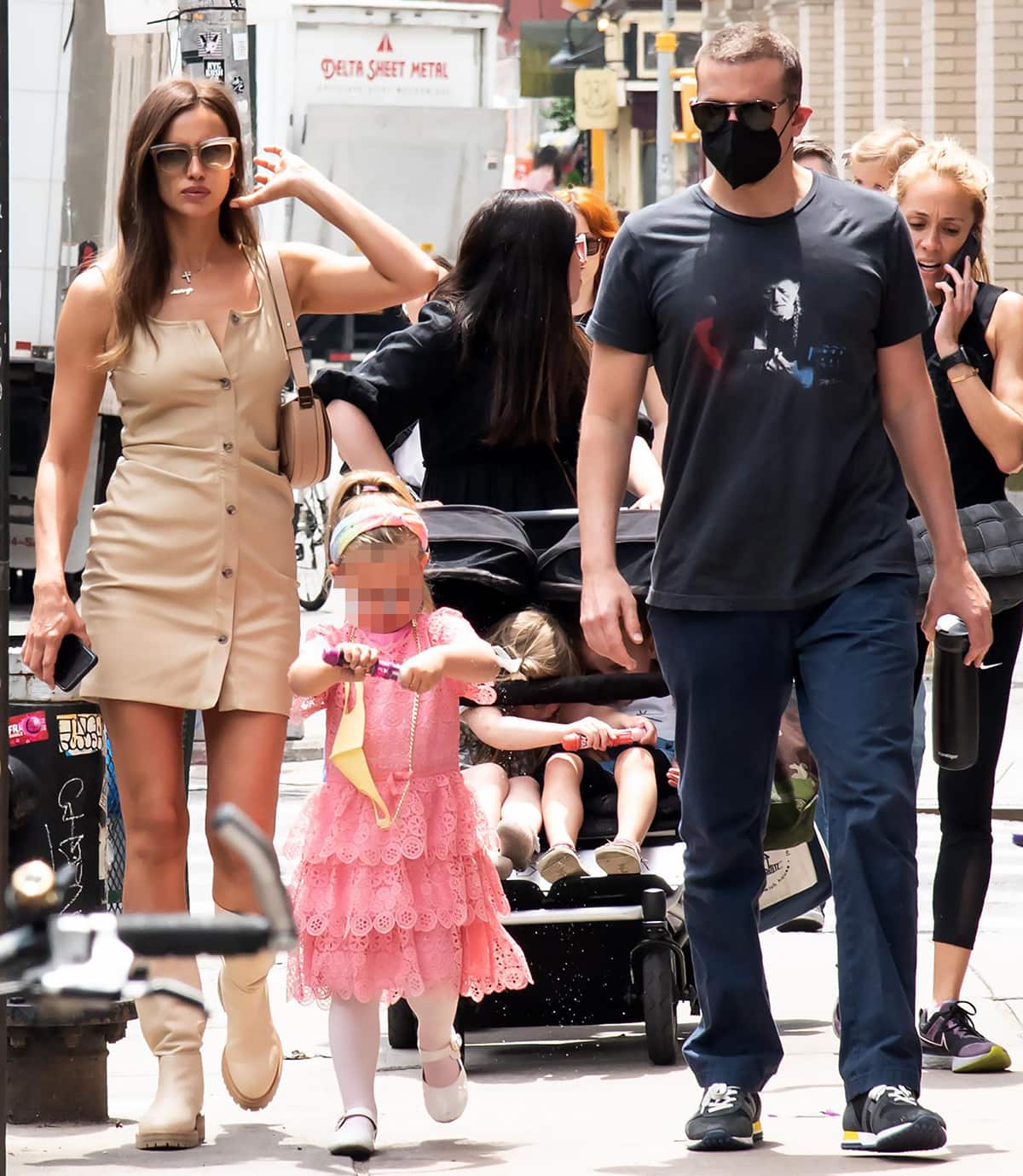Irina Shayk pairs a beige Nanushka vegan leather mini dress with Tamara Mellon x Irina Shayk “Escape” boots, while Bradley Cooper keeps it casual in a graphic T-shirt, navy pants, and sneakers as they stroll through NYC