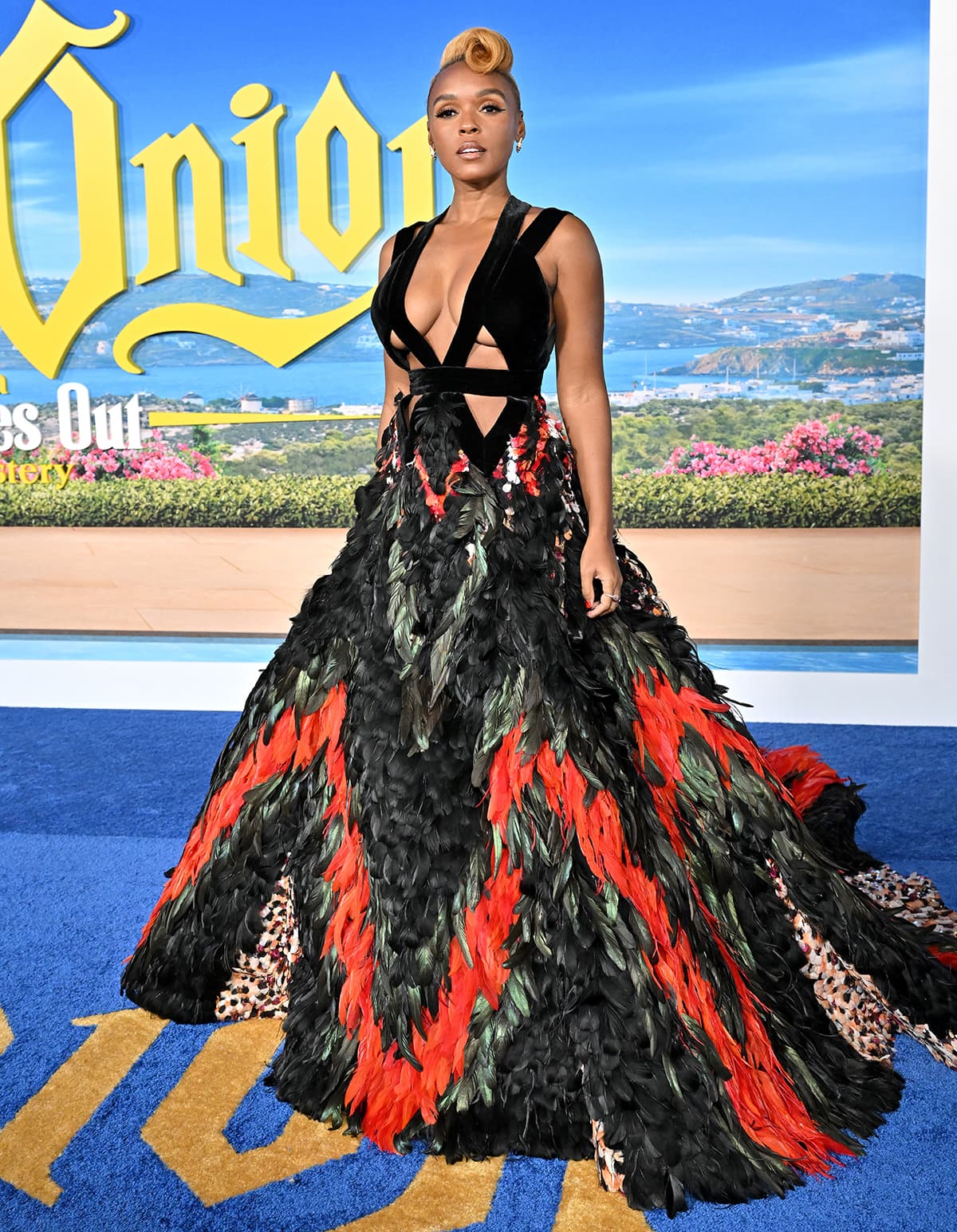 Janelle Monáe turns heads in a dramatic Elie Saab couture gown featuring a cutout velvet bodice and a sweeping skirt covered in bold black, red, and green feathers