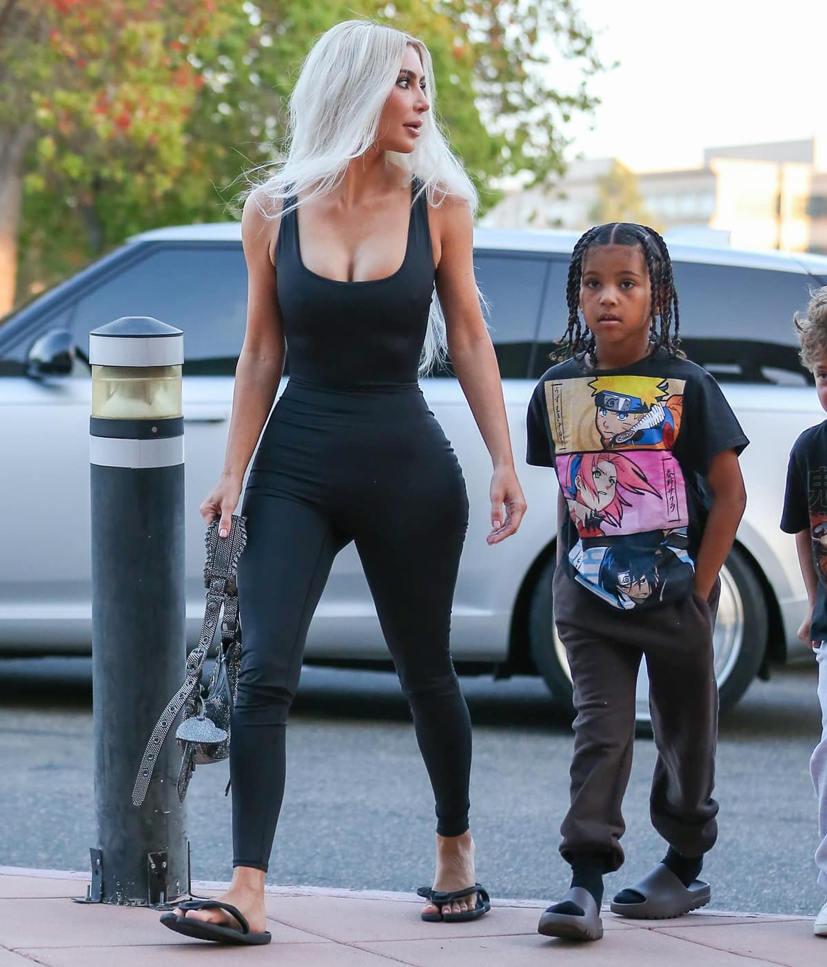 Kim Kardashian keeps it casual in Balenciaga Flip sandals, pairing them with a curve-hugging Skims All in One Shine onesie as she arrives with her son Saint to watch North’s basketball game in Calabasas on October 21, 2022