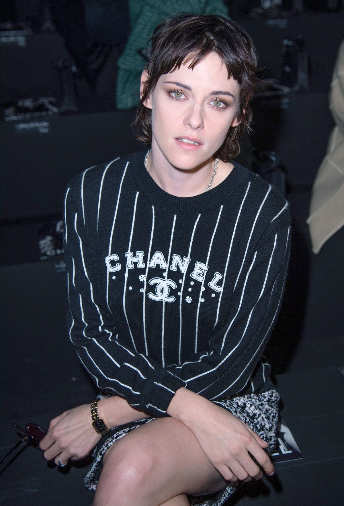 Kristen Stewart is seen in a striking black-and-white striped Chanel sweater featuring the brand's logo, paired effortlessly with a black-and-white tweed mini skirt