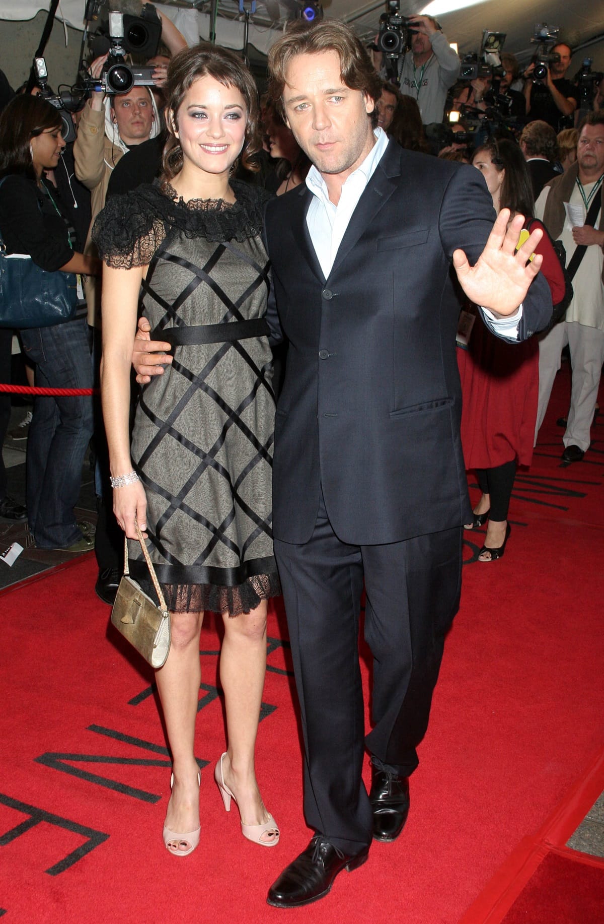 Marion Cotillard and Russell Crowe attend the TIFF premiere of A Good Year on September 9, 2006, with Cotillard wearing a lace-trimmed cocktail dress paired with blush peep-toe heels and a metallic clutch