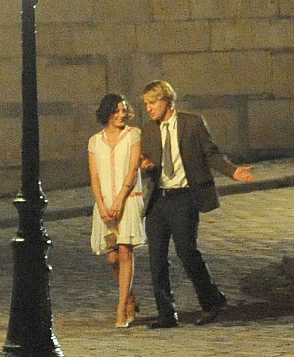 Owen Wilson and Marion Cotillard film a nighttime scene for Midnight in Paris on July 30, 2010, with Cotillard wearing a soft, vintage-inspired dress paired with classic nude heels