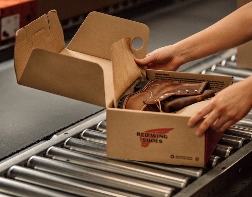 A Red Wing boot being carefully packaged in its branded box, showcasing the brand's commitment to quality craftsmanship and attention to detail