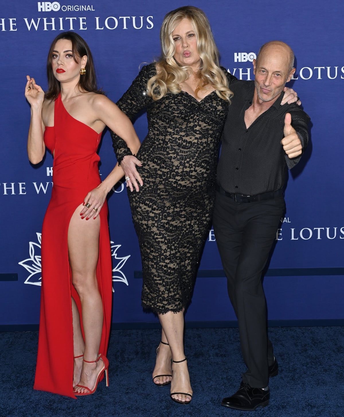 Aubrey Plaza in a red Mônot gown with Stuart Weitzman sandals, Jennifer Coolidge in a black lace Dolce Gabbana dress with ankle-strap heels, and Jon Gries attend the Los Angeles Season 2 premiere of The White Lotus at Goya Studios on October 20, 2022