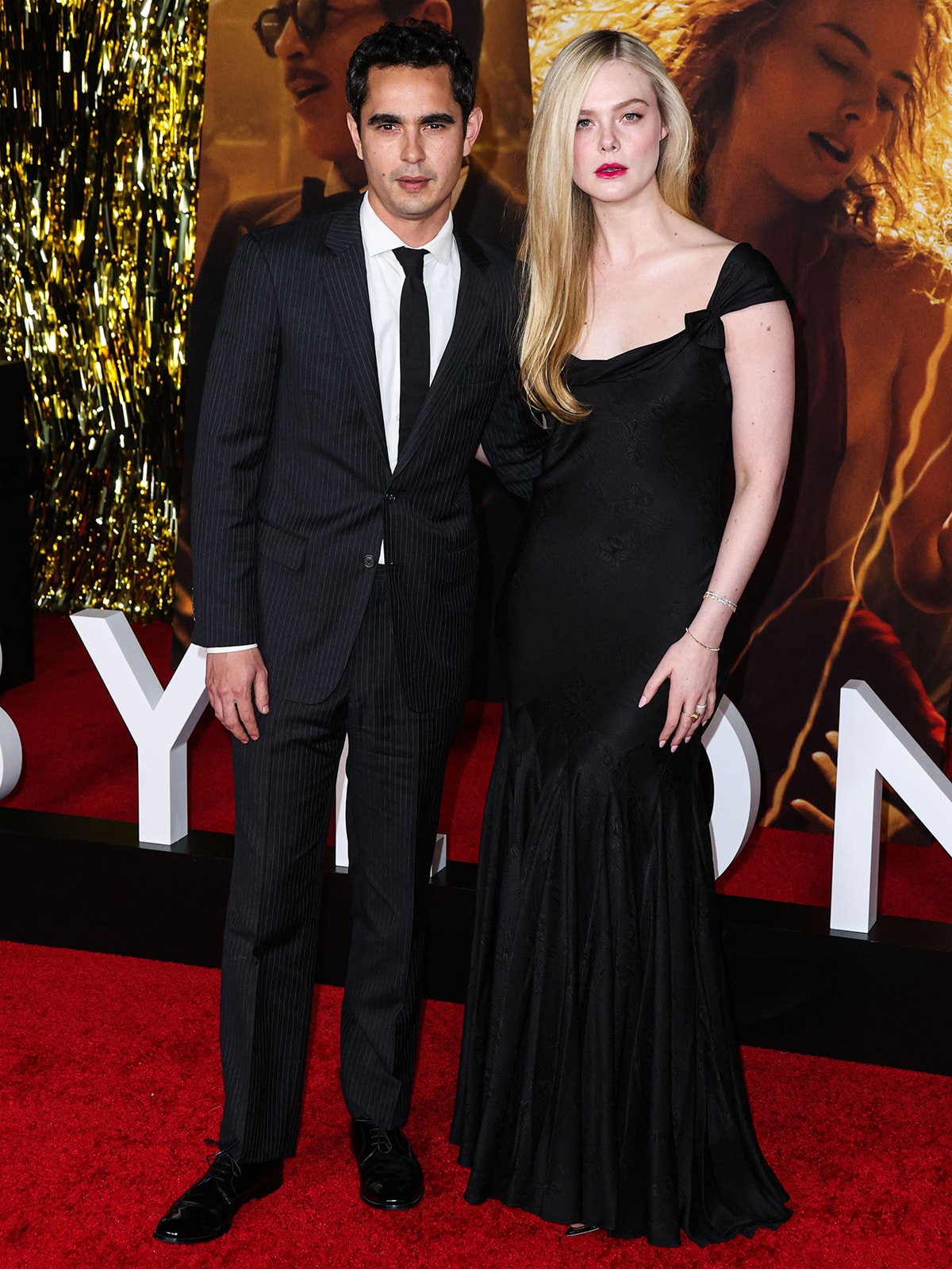 Max Minghella and Elle Fanning make a rare red-carpet appearance together at the Babylon premiere, with Fanning elegant in a vintage black Alexander McQueen gown