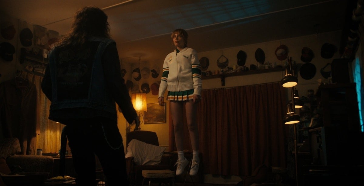 Grace Van Dien floats midair in a chilling scene as Chrissy Cunningham, wearing her Hawkins High cheer uniform in Stranger Things Season 4's haunting premiere episode