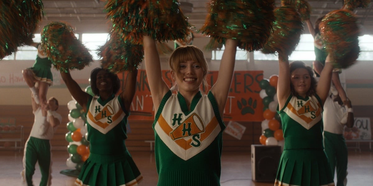 Grace Van Dien wears a retro green and gold cheerleading uniform as Chrissy Cunningham, the Hawkins High head cheerleader, in Season 4 of Stranger Things