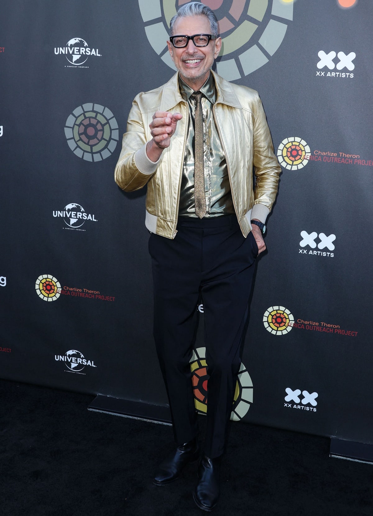 Jeff Goldblum, standing at 6'4 ¼" (193.7 cm), lit up the 2022 Charlize Theron Africa Outreach Project Summer Block Party in Los Angeles with his signature flair, rocking a metallic gold bomber jacket, matching shirt and tie, tailored trousers, and sleek black boots