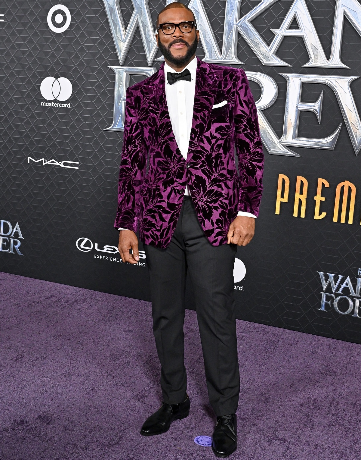 Tyler Perry, standing at 6'4 ¼" (193.7 cm), brought bold elegance in a Tom Ford outfit to the Black Panther: Wakanda Forever premiere in Los Angeles with a velvet plum floral tuxedo jacket, classic bow tie, and glossy black dress shoes that made a statement on the purple carpet