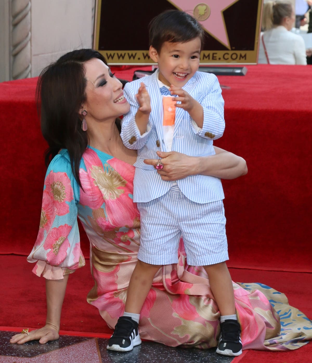 Lucy Liu looked radiant in a Peter Pilotto Spring 2019 one-shoulder floral silk gown, while her son Rockwell Lloyd Liu stole hearts in a striped seersucker suit paired with black Adidas sneakers