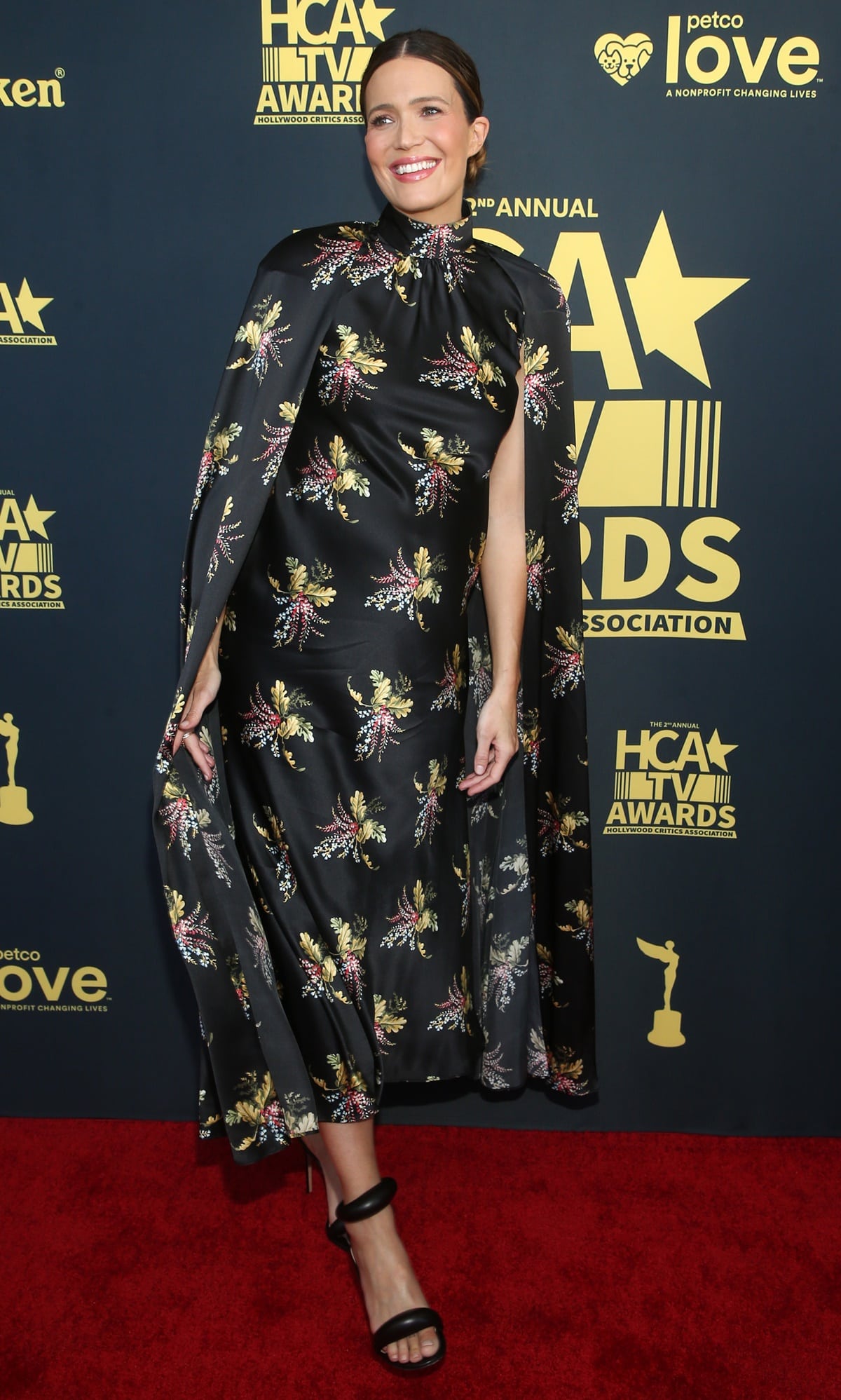 Mandy Moore turned heads at the 2nd Annual HCA TV Awards: Broadcast Cable on August 13, 2022, in Beverly Hills, wearing a black silk floral cape dress from Rodarte’s Fall 2022 collection, styled with sleek Gianvito Rossi Bijoux 105 leather sandals