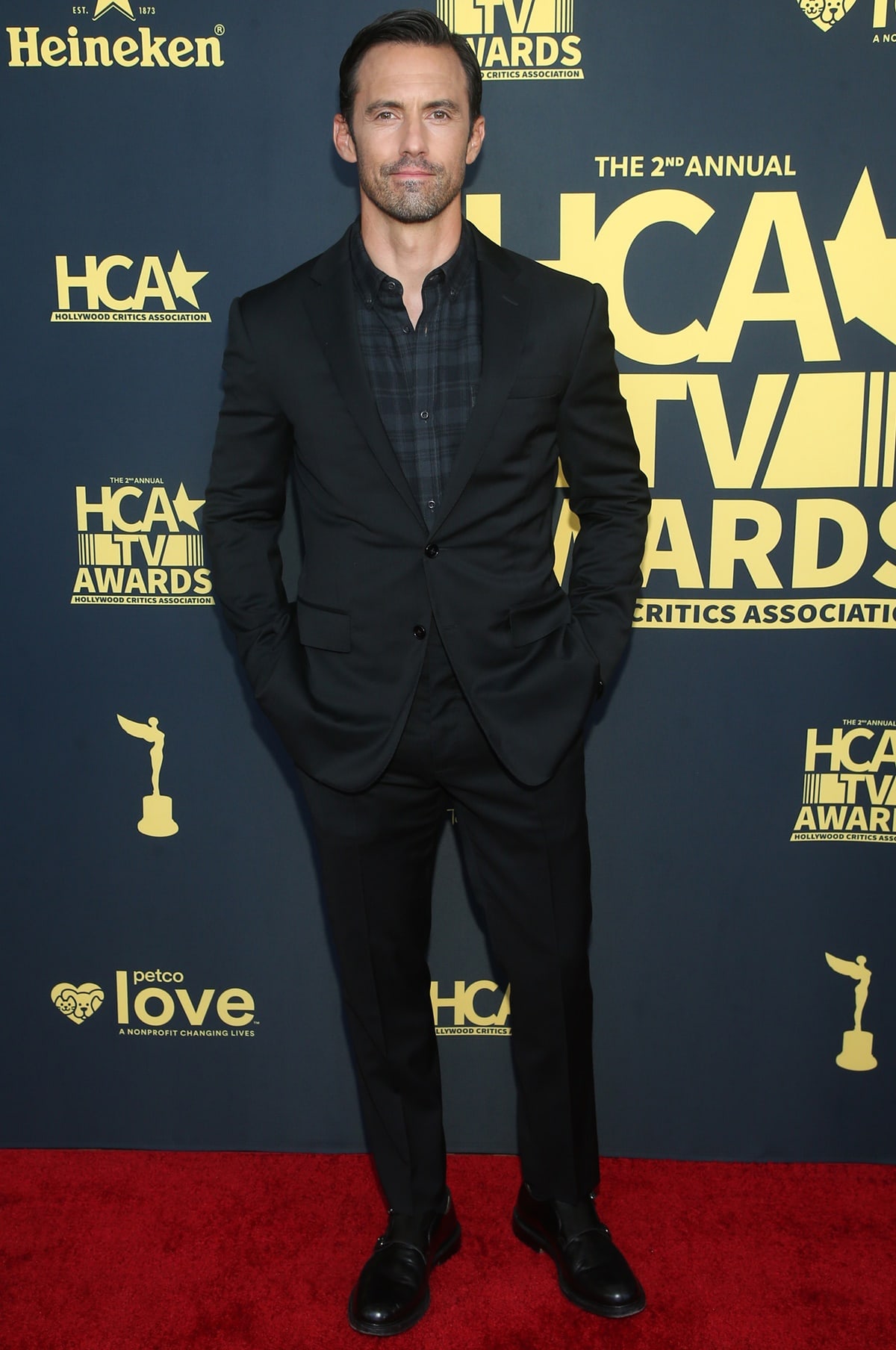 Milo Ventimiglia attended the 2nd Annual HCA TV Awards in Beverly Hills on August 13, 2022, looking sharp in a sleek all-black suit, a subtle plaid dress shirt, and polished black dress shoes that grounded the sophisticated look with understated elegance