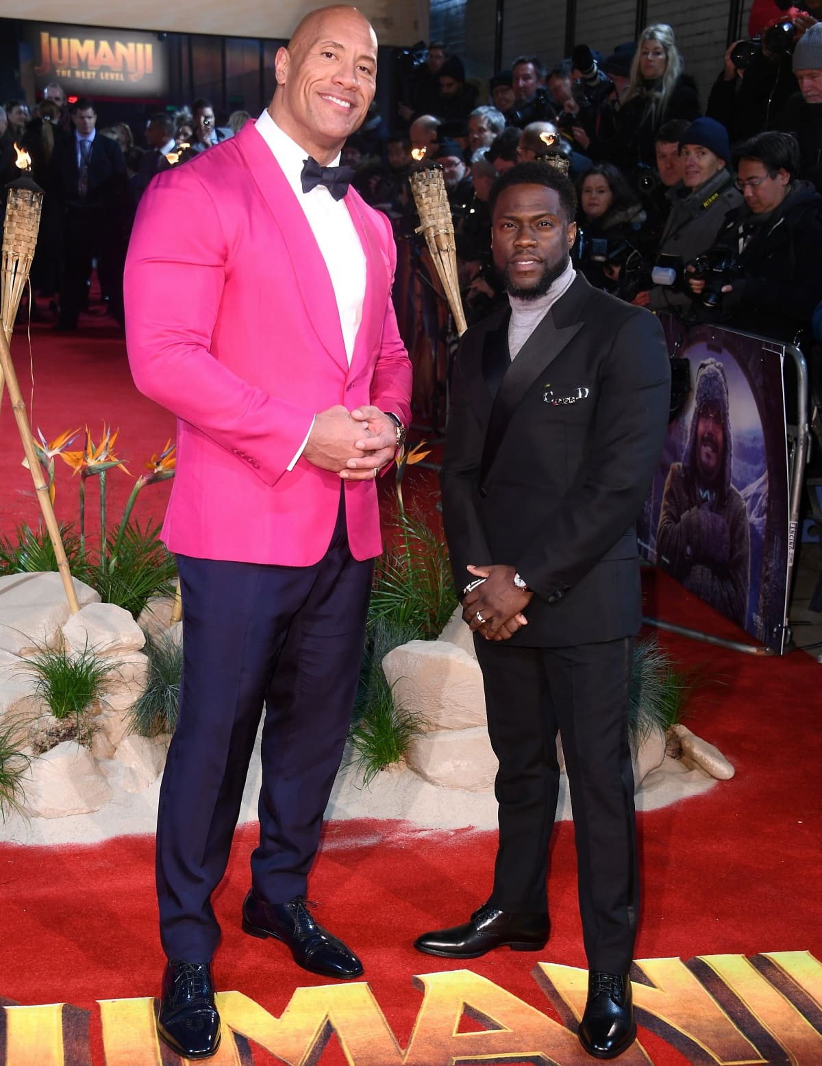 Dwayne “The Rock” Johnson steps out in polished navy patent-leather oxfords that mirror his sharp tailoring, while Kevin Hart keeps things classic in sleek black lace-up dress shoes — a subtle but striking footwear contrast at the Jumanji: The Next Level premiere in London, England, on December 5, 2019