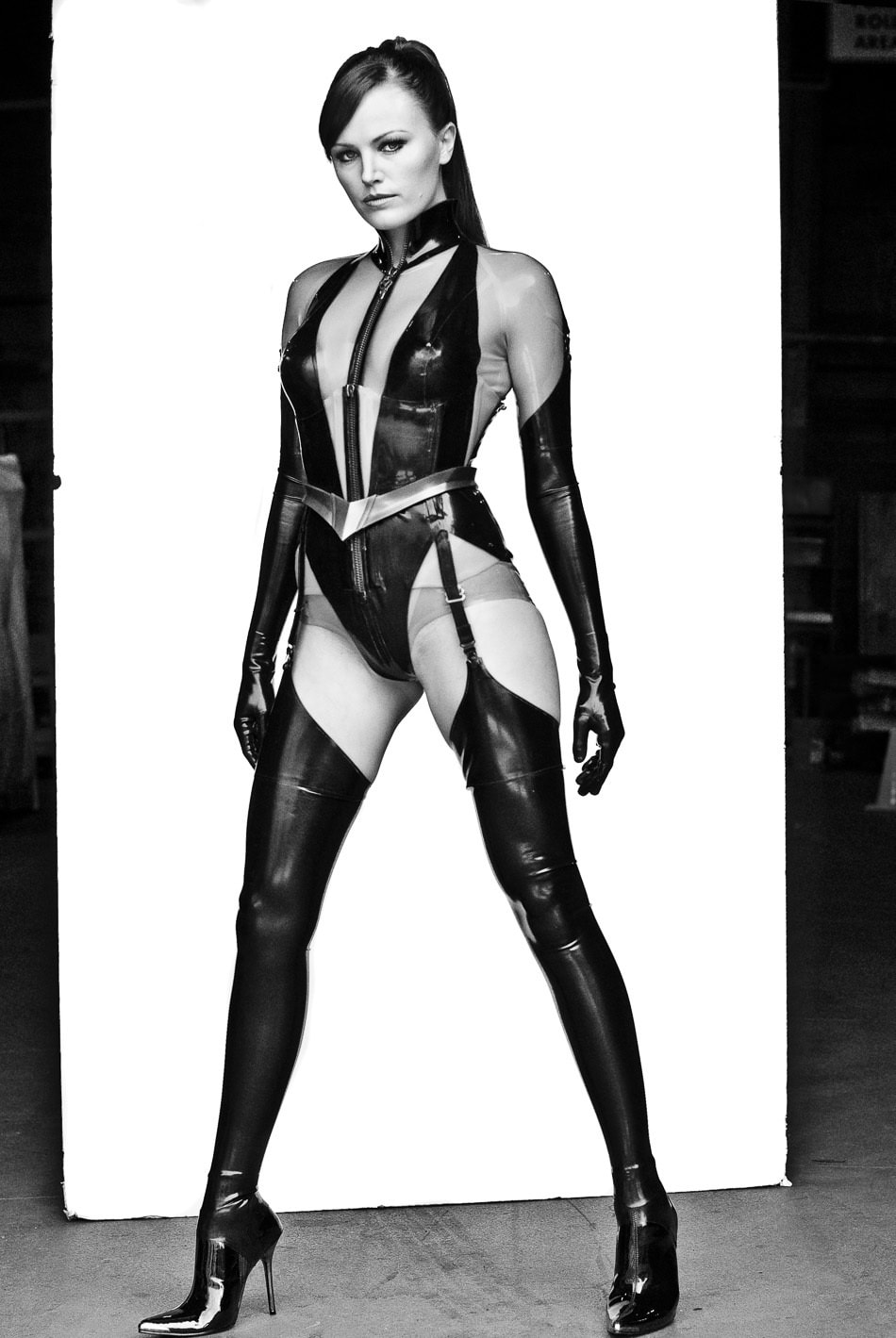Malin Akerman strikes a commanding pose in a Watchmen promo shot, showcasing her full latex-clad Silk Spectre II costume, complete with sleek thigh-high boots and pointed stiletto heels