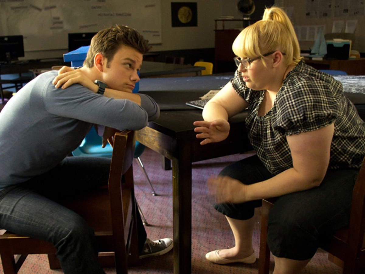 Chris Colfer as Carson Phillips and Rebel Wilson as Malerie Baggs share a quiet classroom moment in Struck by Lightning (2012), with Rebel dressed casually in a plaid top, cropped pants, and cream ballet flats that underscore her character’s down-to-earth charm