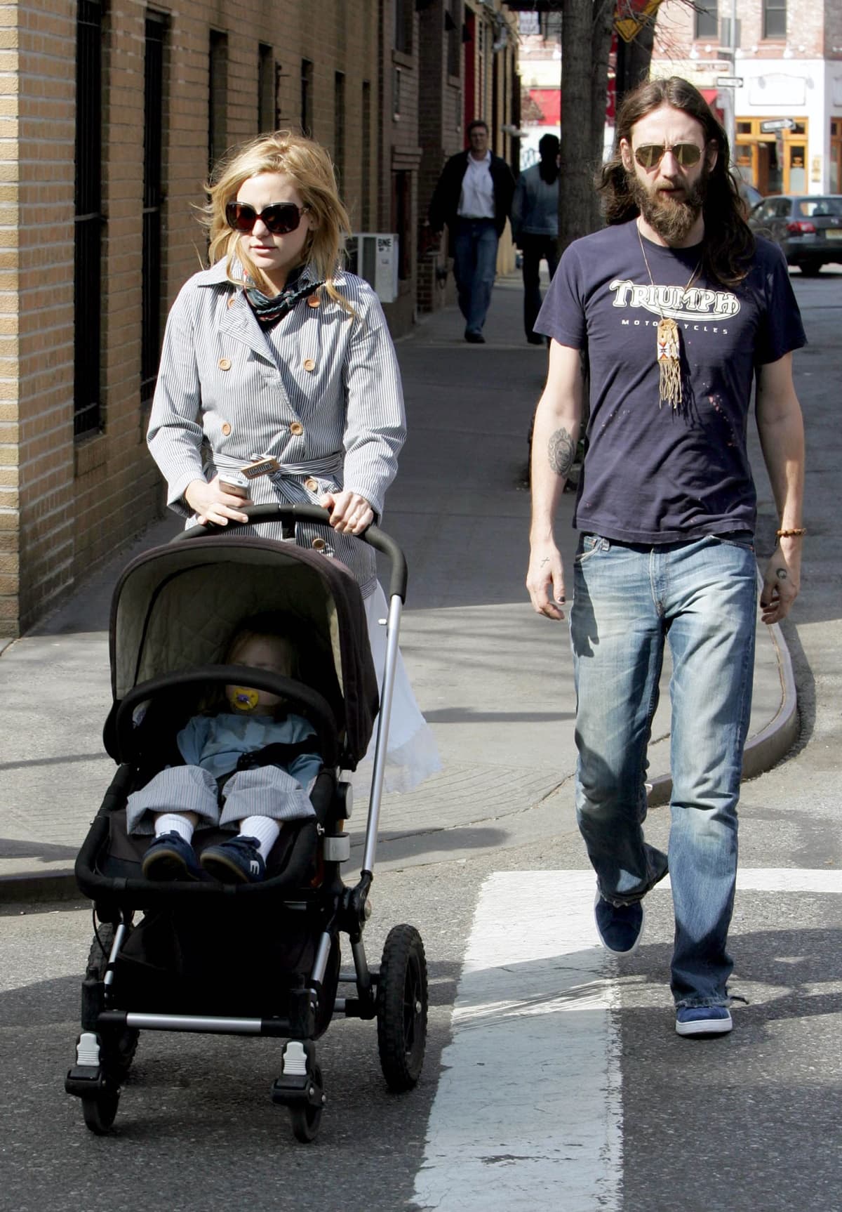 Kate Hudson keeps it casual-chic in a striped trench coat and oversized sunglasses while strolling with then-husband Chris Robinson, who opts for a laid-back look in jeans and a Triumph T-shirt
