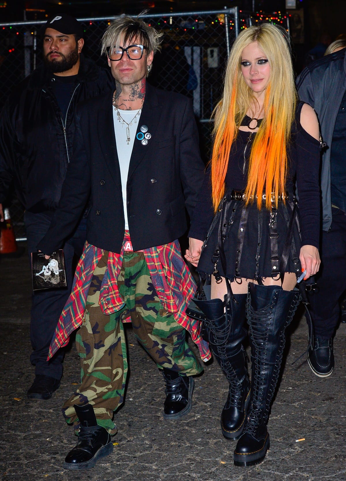 Avril Lavigne and Mod Sun channeled peak pop-punk energy while out in New York City, with Avril rocking towering lace-up Dr. Martens over-the-knee boots and Mod Sun pairing camo pants with plaid and punk accessories