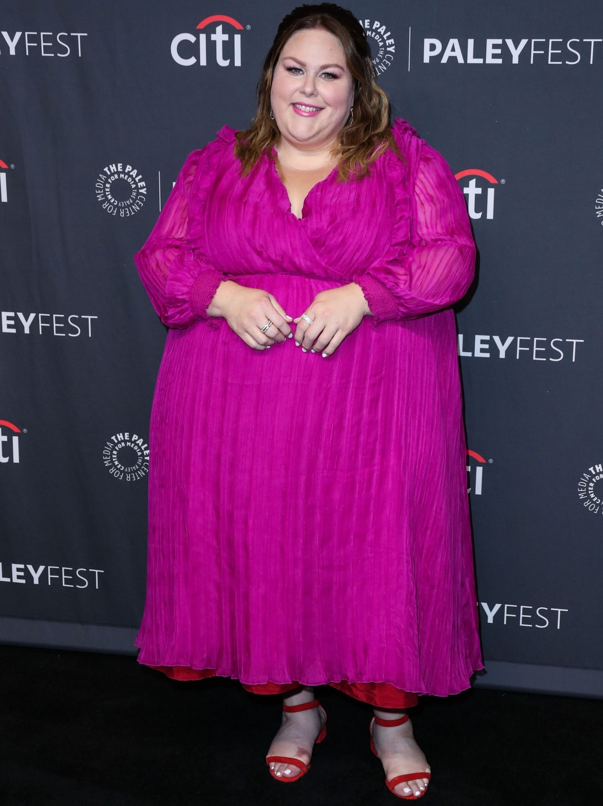 Chrissy Metz shines in a vibrant magenta pleated dress paired with bold red sandals at PaleyFest LA