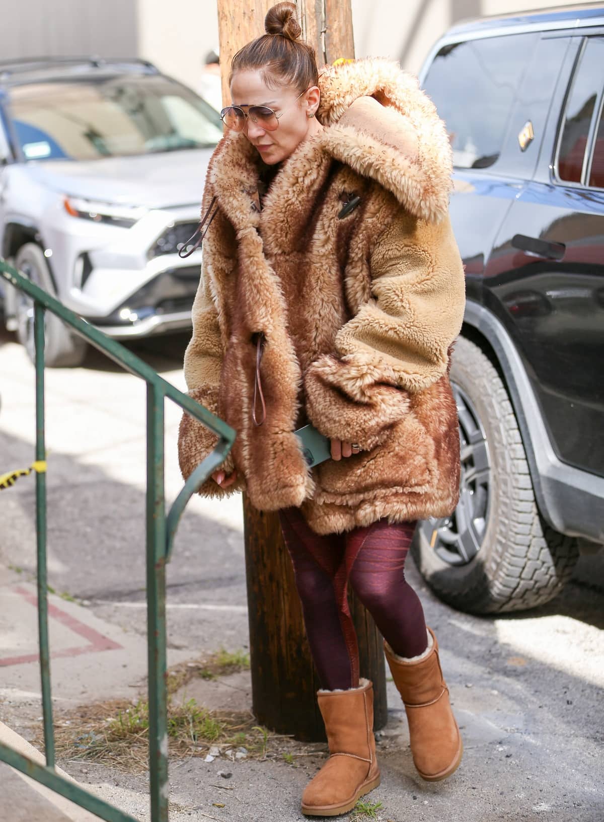 Jennifer Lopez bundles up in an oversized Coach x Schott shearling coat, maroon leggings, and chestnut Ugg Classic Short boots for a luxe-meets-cozy winter look