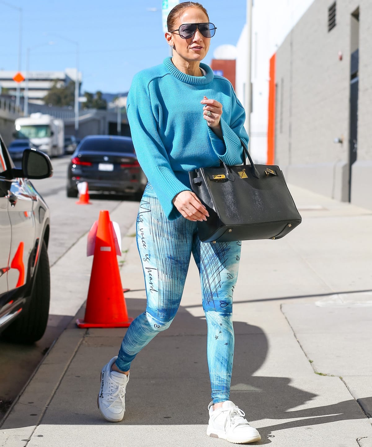 Jennifer Lopez steps out in a sky-blue A.L.C. sweater, printed Niyama Sol leggings, and crisp Off-White sneakers paired with a classic black Hermès Birkin bag