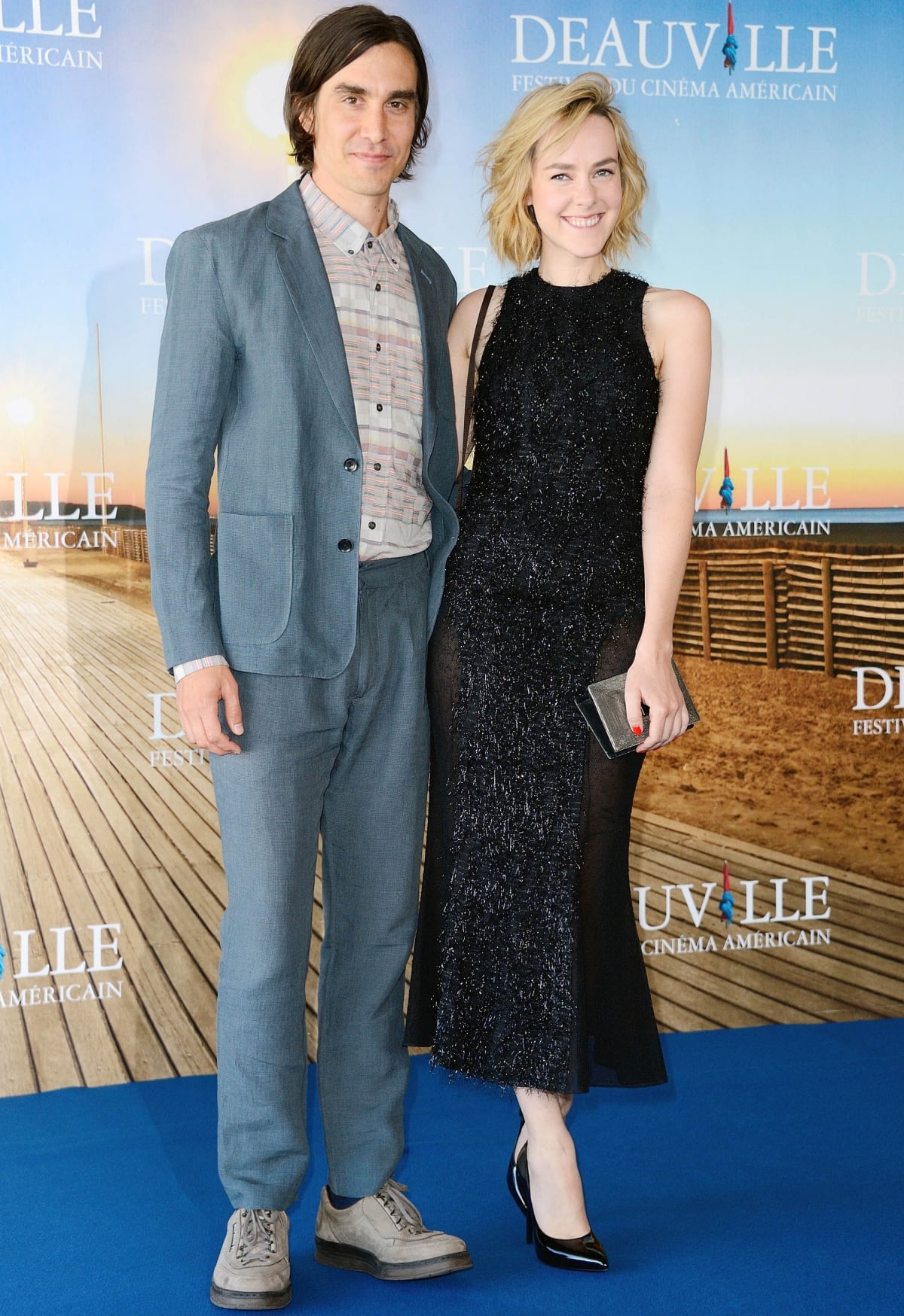 M. Blash and Jena Malone attend The Wait photocall at the 39th Deauville American Film Festival in France on September 2, 2013, with Jena wearing a sleeveless black Wes Gordon metallic eyelash-chiffon dress and glossy black Saint Laurent pumps
