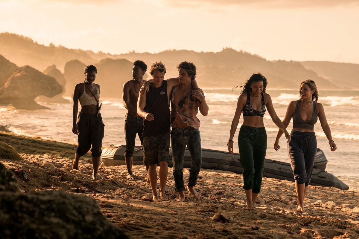 The Pogues walk barefoot along a sunlit beach in Outer Banks, exuding carefree energy and unbreakable camaraderie as their high-stakes journey continues